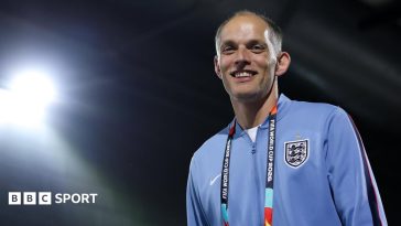 Thomas Tuchel smiles in England training kit with a World Cup 2026 lanyard around his neck